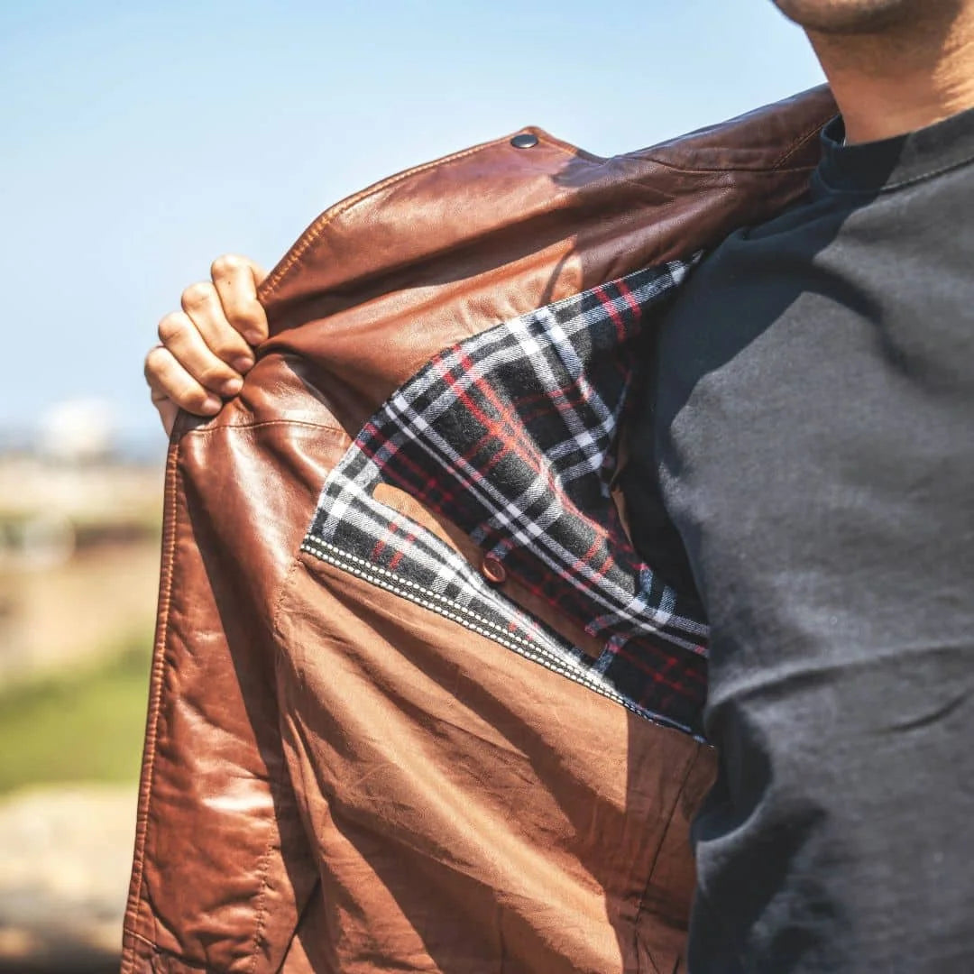 The interior of a brown leather jacket for men is seen to have a checkered cotton lining
