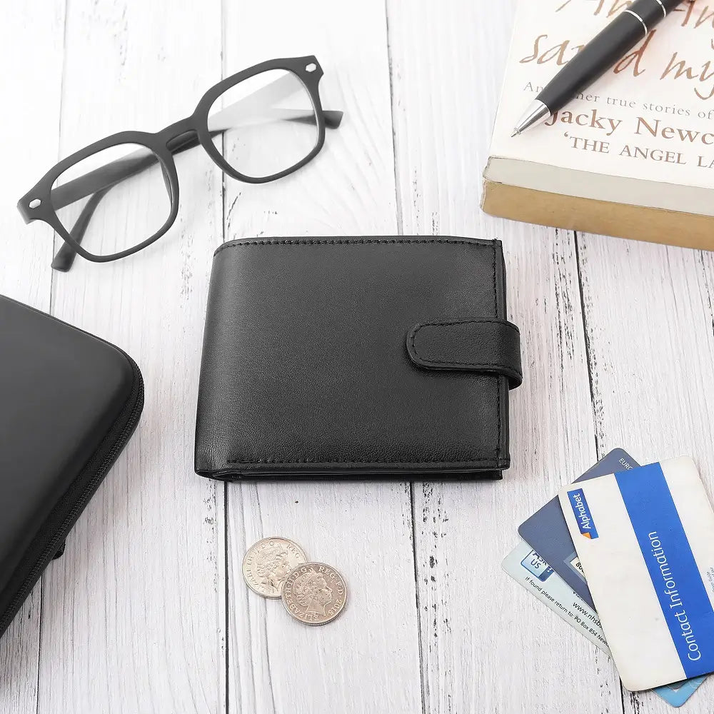 Flat lay of Basic Wallet Style 99 black leather RFID bifold wallet with tab closure, shown with coins, cards, and glasses