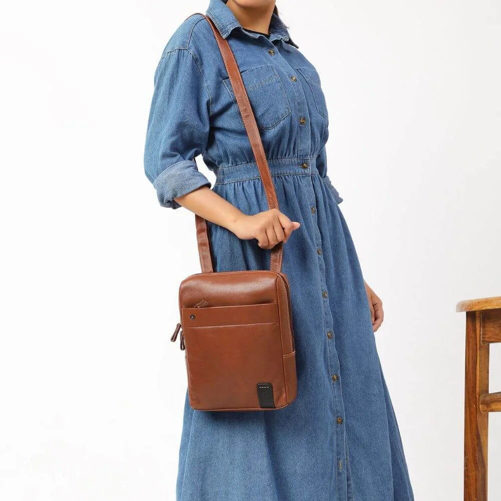 Brown Tuscan leather messenger bag with adjustable crossbody strap, shown worn over shoulder.