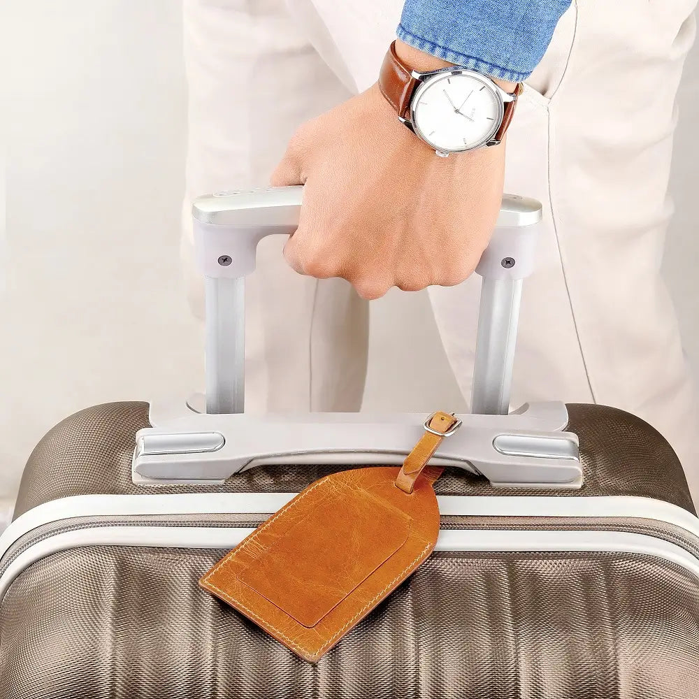 Tan leather luggage tag attached to a suitcase, adding a refined and classic travel touch.