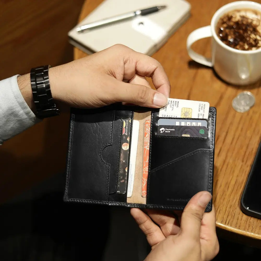 Open black leather vertical card wallet held in hand showing card slots and slip pockets