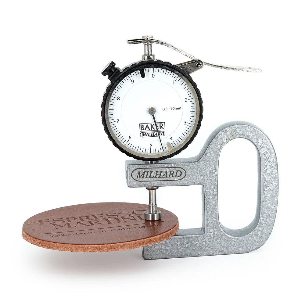 A Milhard dial thickness gauge measuring a round piece of brown leather labeled ‘Espresso Martini,’ showing a reading of approximately 4.4 millimeters on the dial.