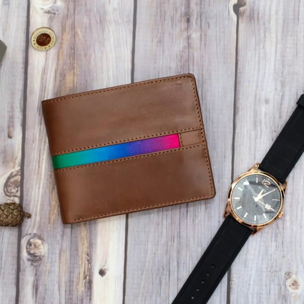 Brown leather wallet with rainbow stripe and watch on wooden surface
