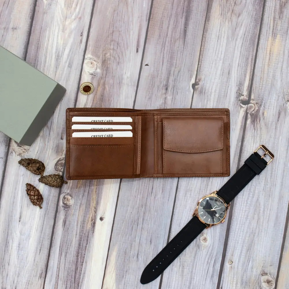 Brown leather wallet with colorful stripe and black watch on wooden surface