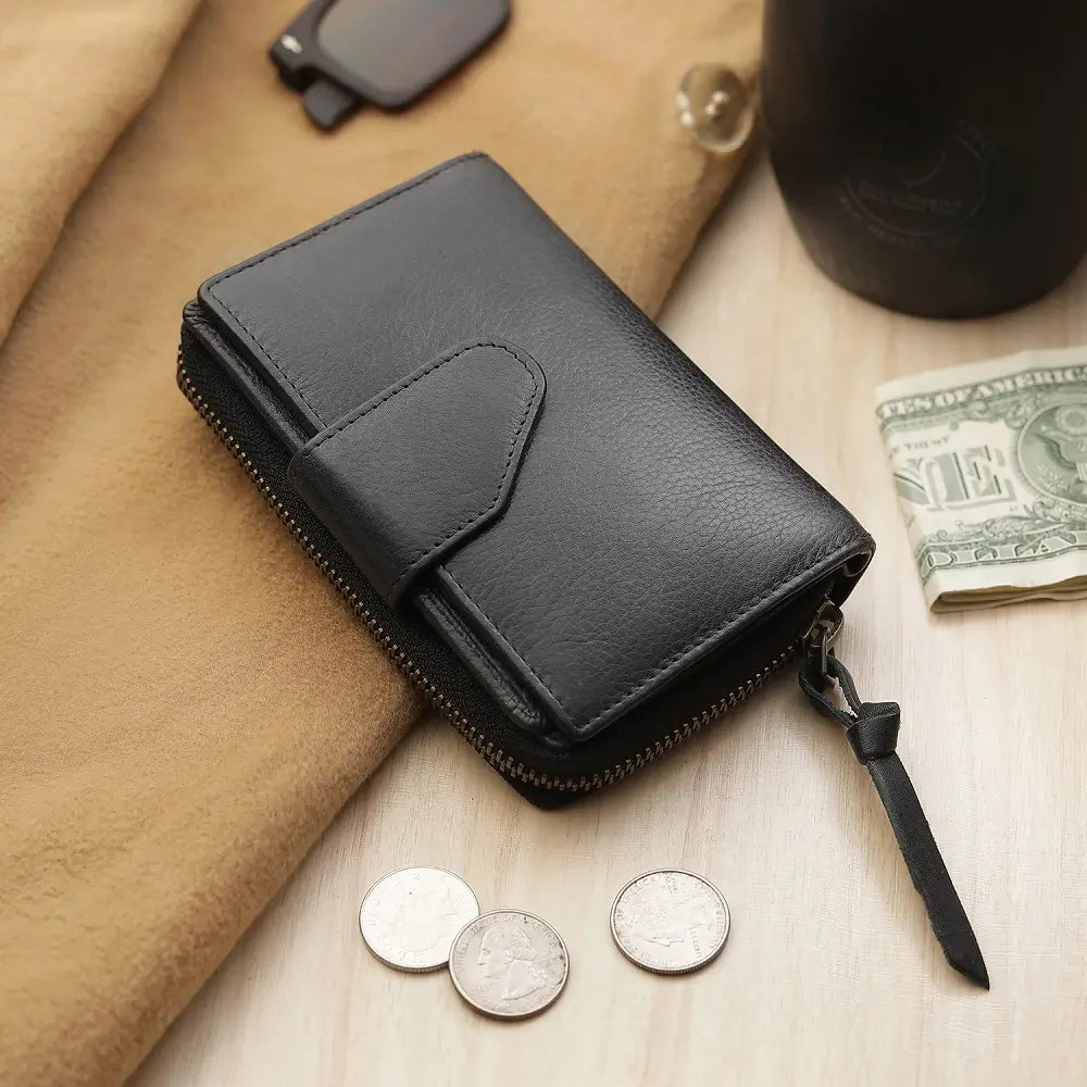 Black leather wallet with coins and money on a wooden surface