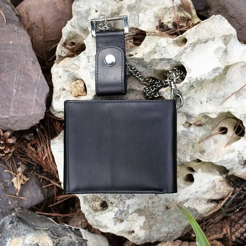 Black leather wallet with keychain on a rocky surface