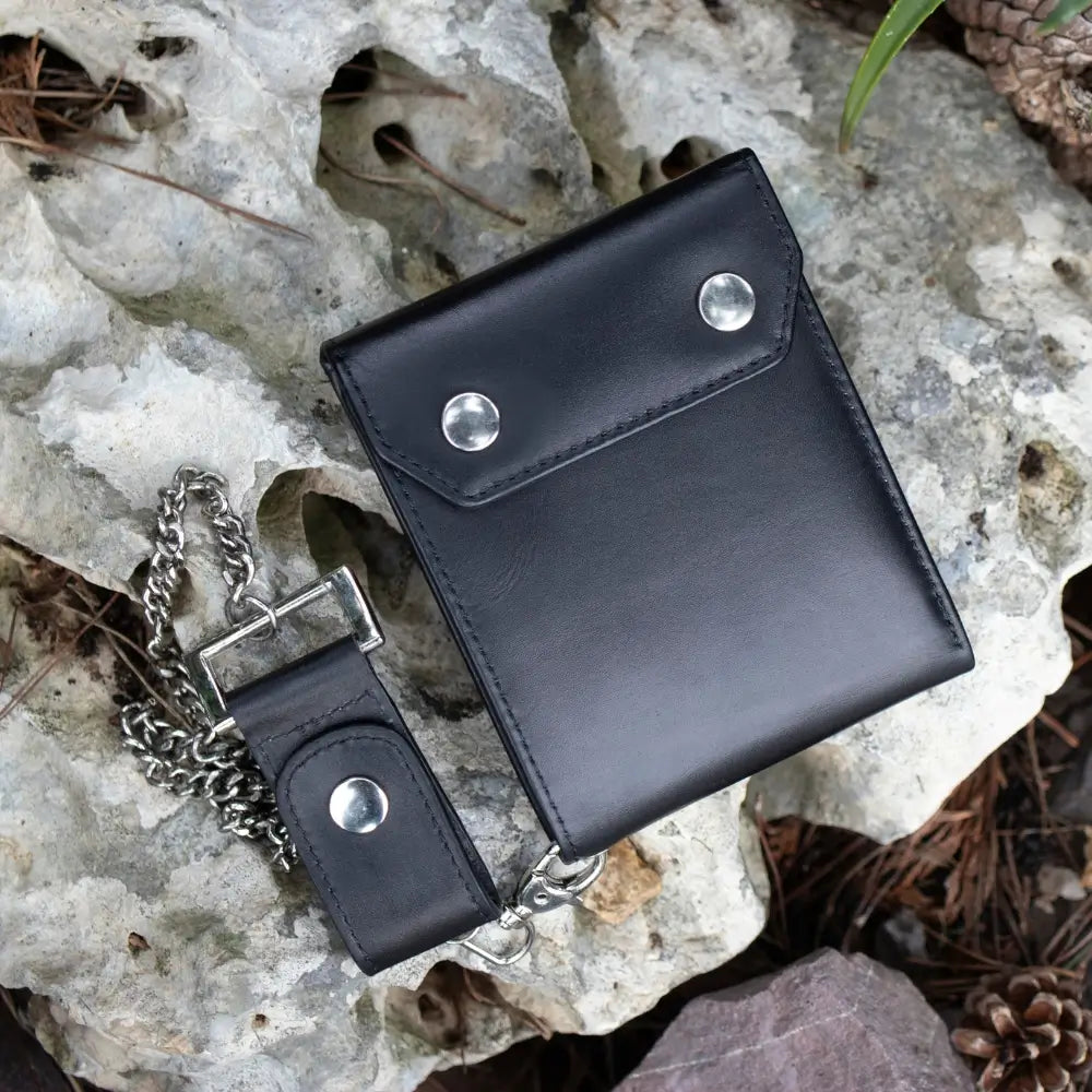 Black leather wallet with chain on a rocky surface