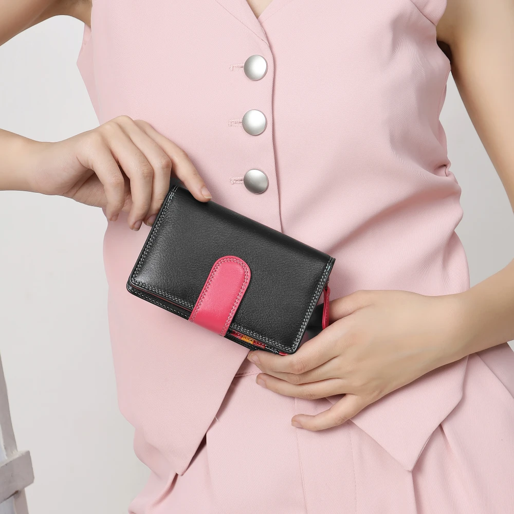 Person holding a black and pink wallet with a light pink background