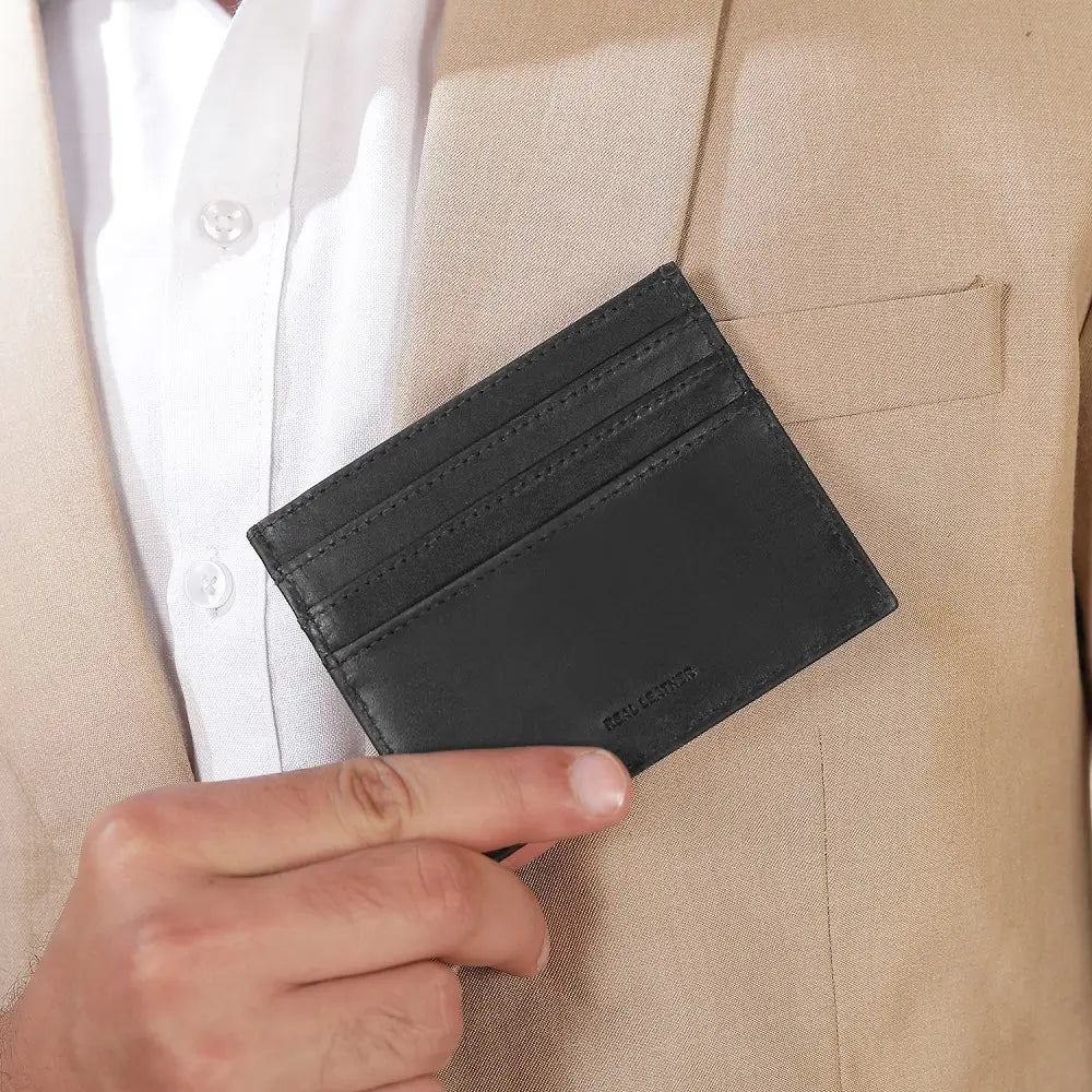 Person holding a black leather cardholder against a beige suit background