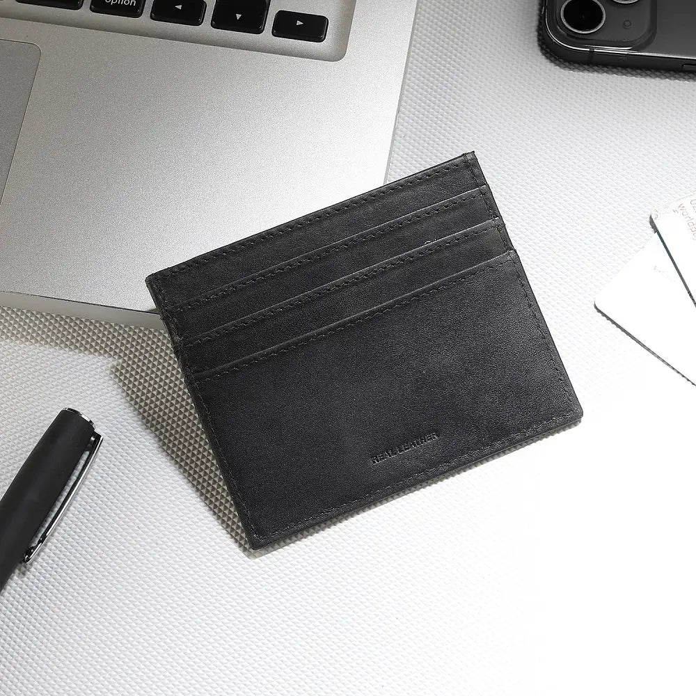Black leather cardholder on a white surface with a pen and phone in the background