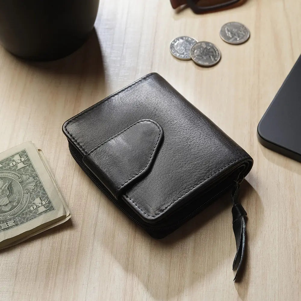 Black leather wallet on a wooden surface with coins and a phone