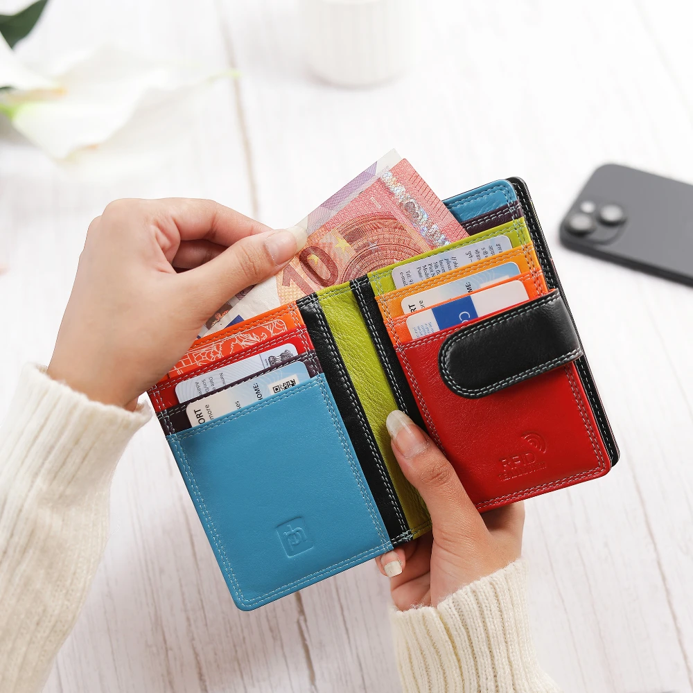 Multicolored wallet with cards and money held by a person, with a blurred background