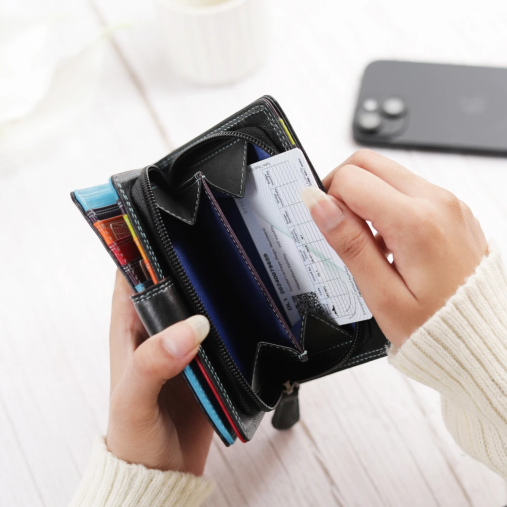 Person holding a black wallet with multiple card slots and a checkbook, with a blurred phone in the background.