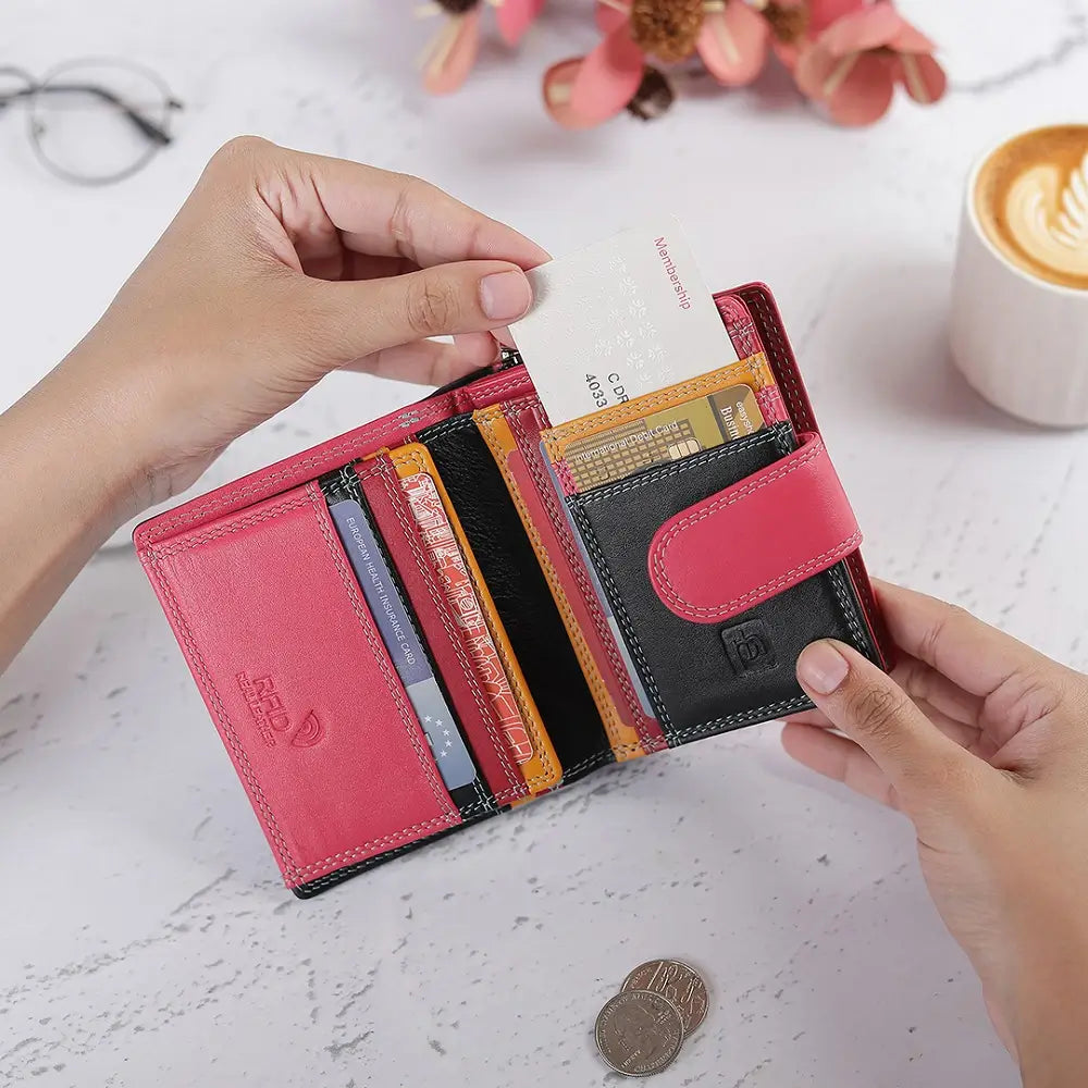 Person opening a red wallet with cards and coins on a marble surface.
