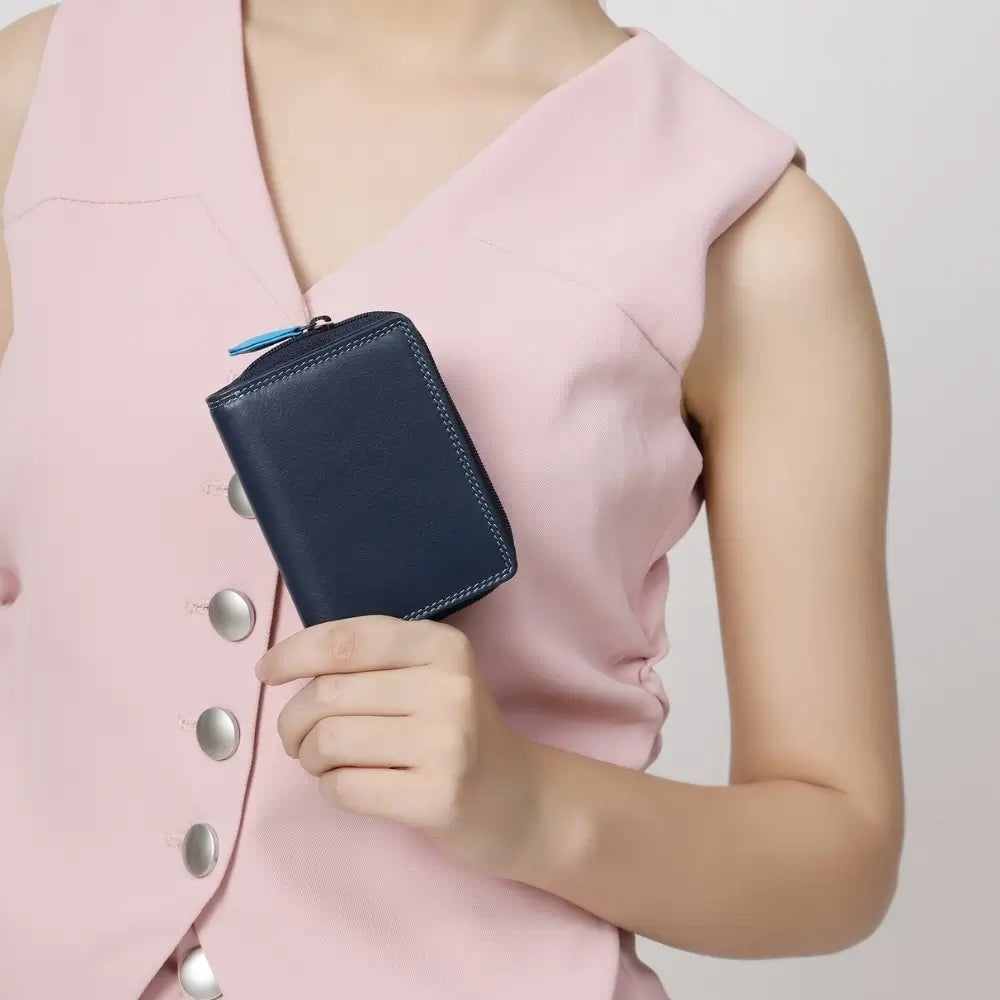 Person holding a blue wallet against a light pink background