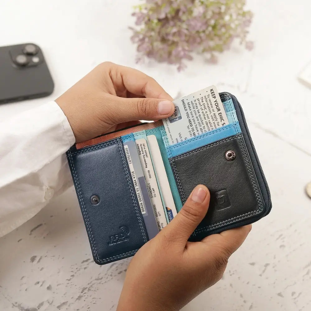 Person holding a blue wallet with cards and a phone in the background