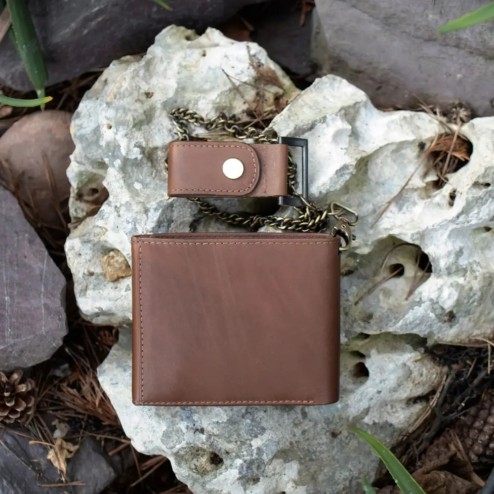 Brown leather wallet with chain on a rocky surface