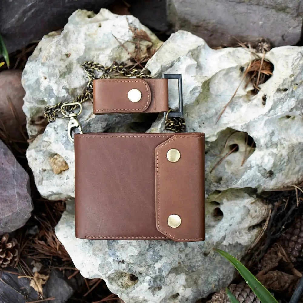 Brown leather wallet with chain on a rocky surface