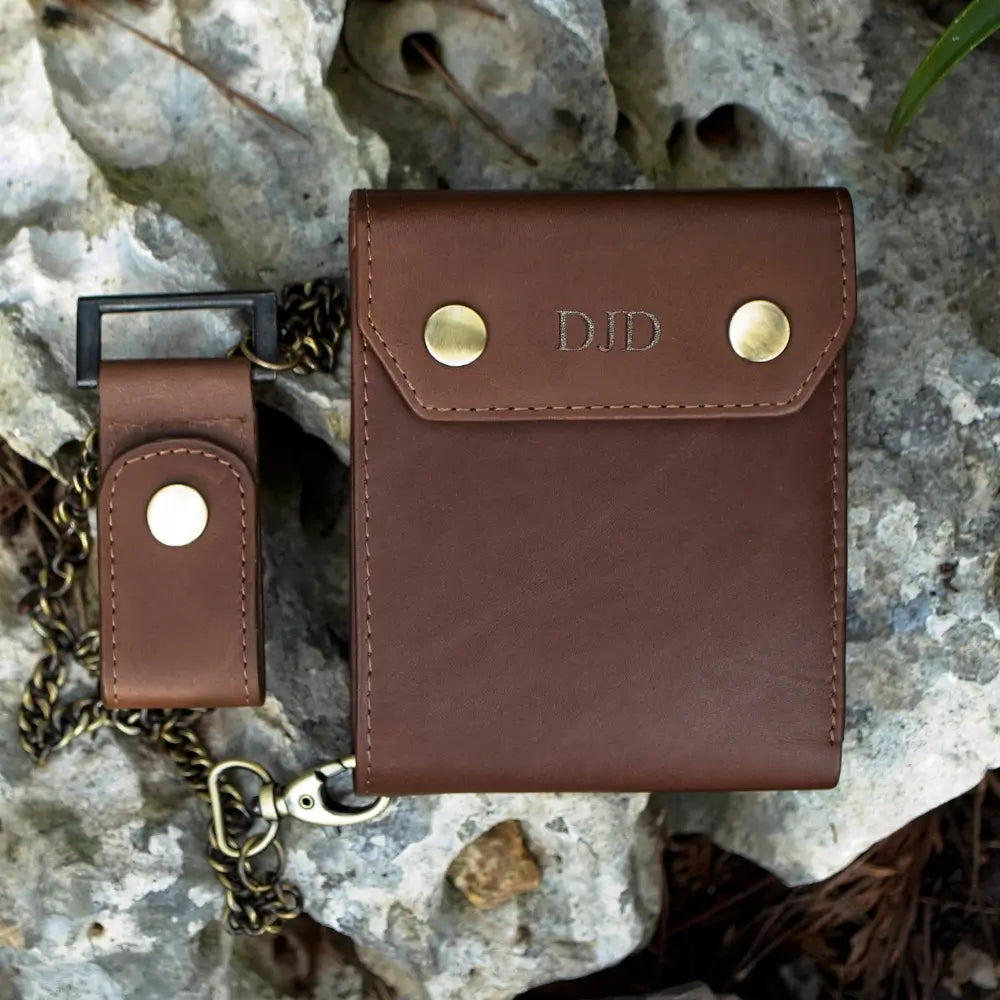 Brown leather wallet with gold accents on a textured stone surface