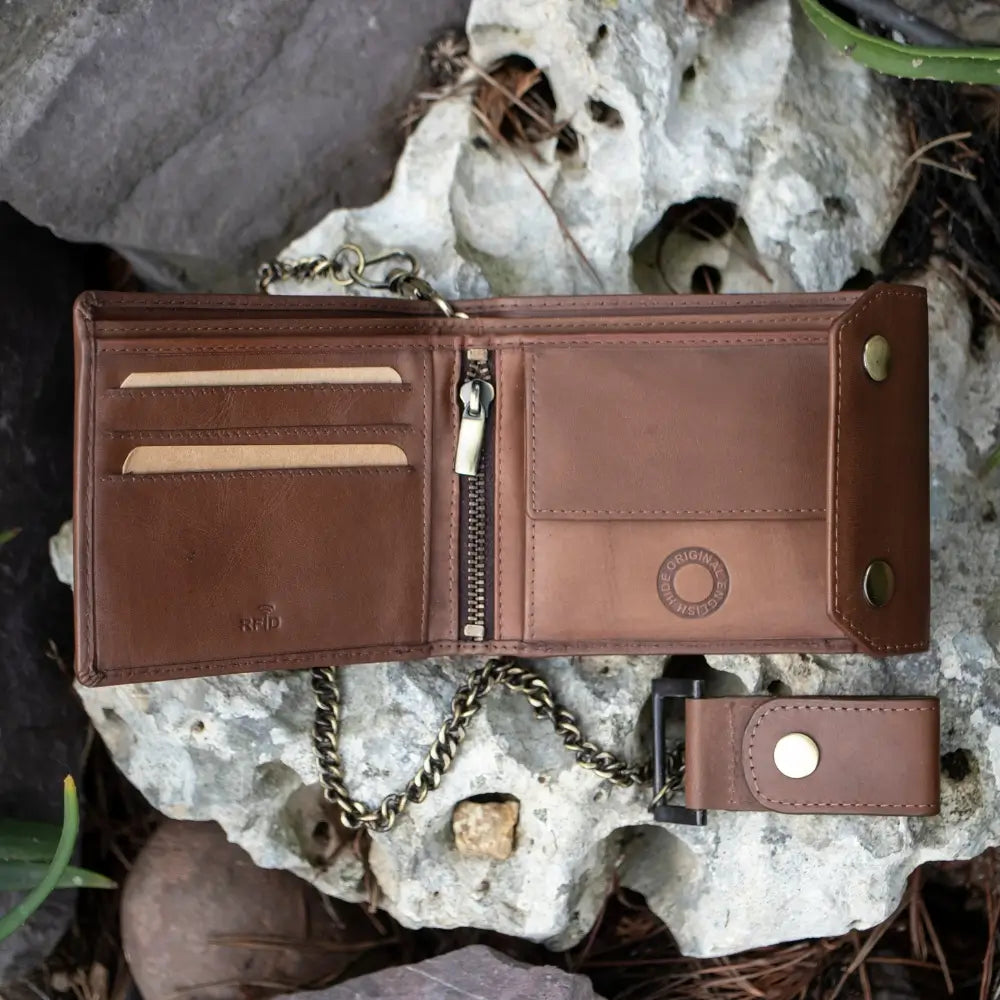 Brown leather wallet with chain on a rocky surface