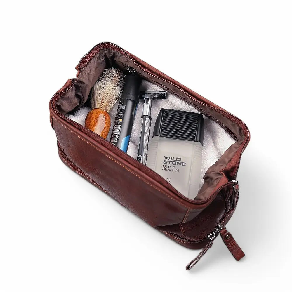 Open brown leather toiletry bag with grooming products on a white background