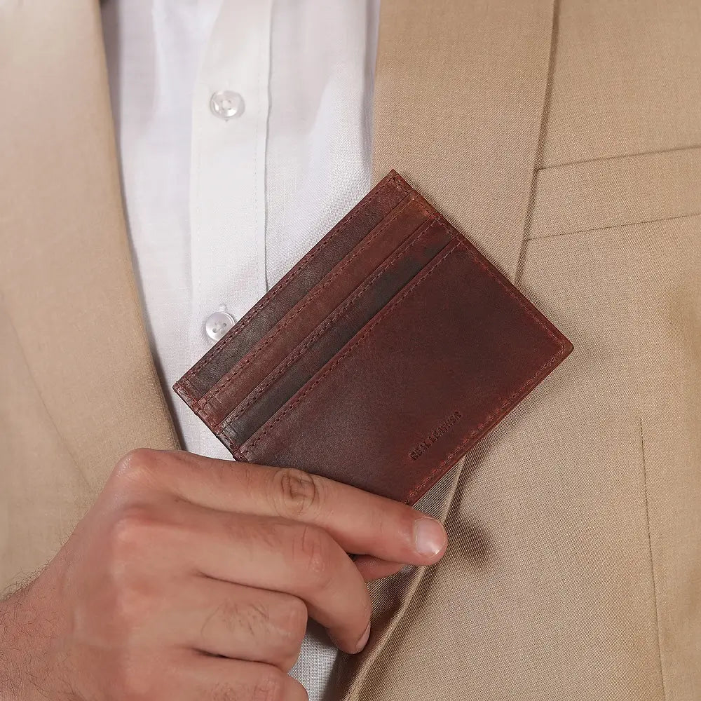 Brown leather card holder being inserted into a beige suit pocket.