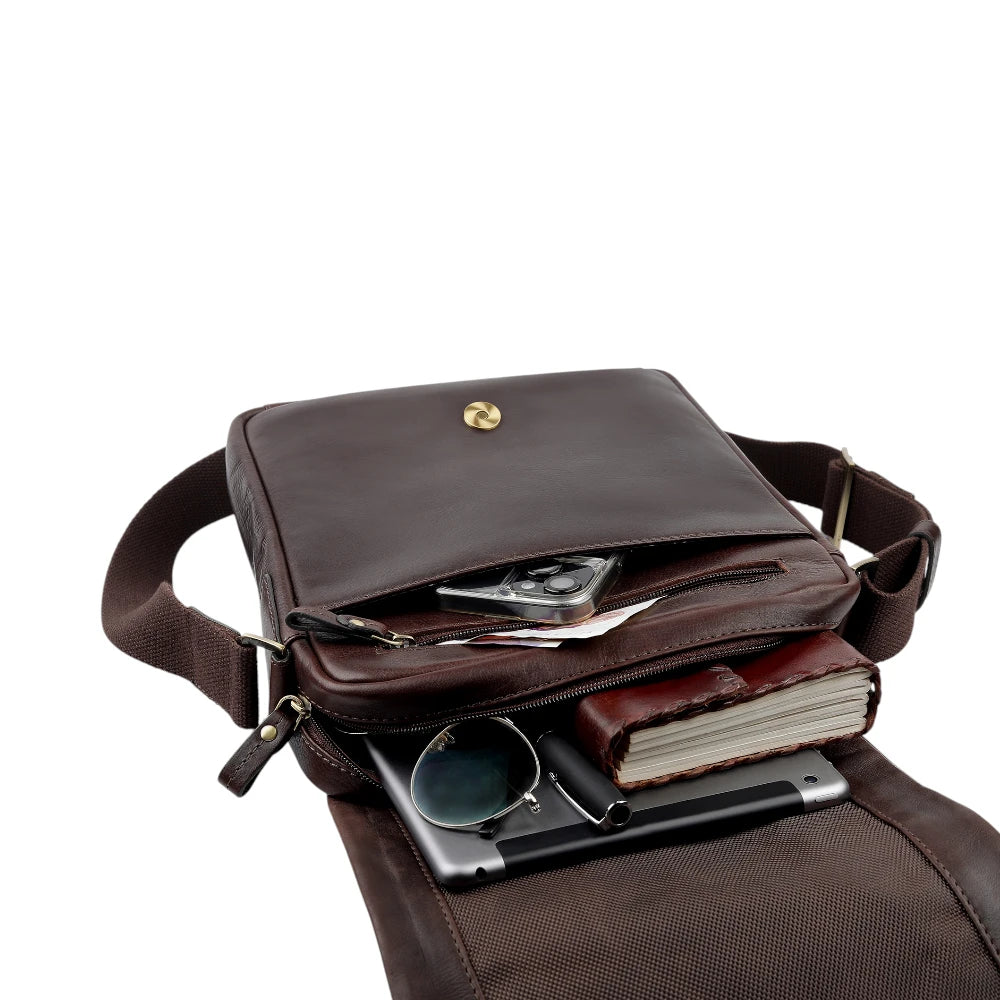 Brown leather crossbody bag with items inside on a white background
