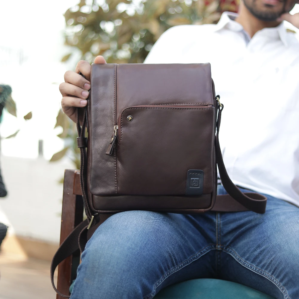 Person holding a brown leather backpack outdoors