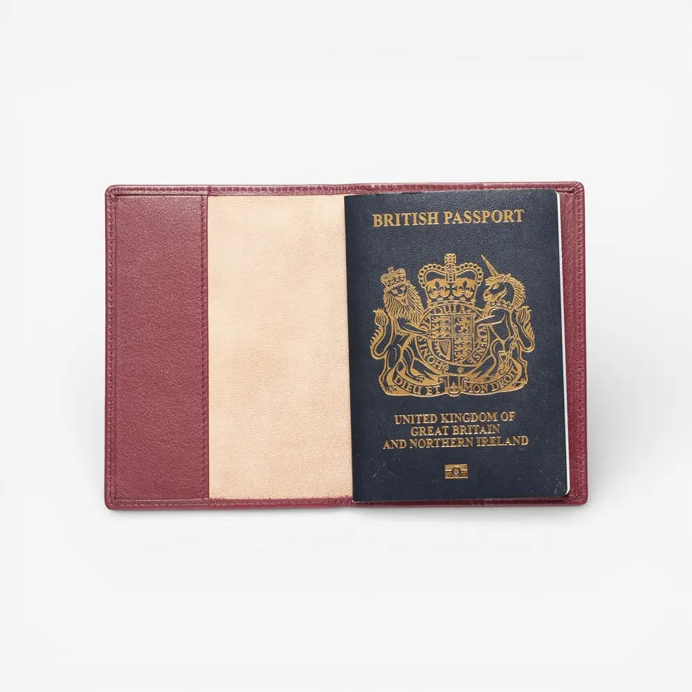 Burgundy Passport cover with a British passport inside on a white background