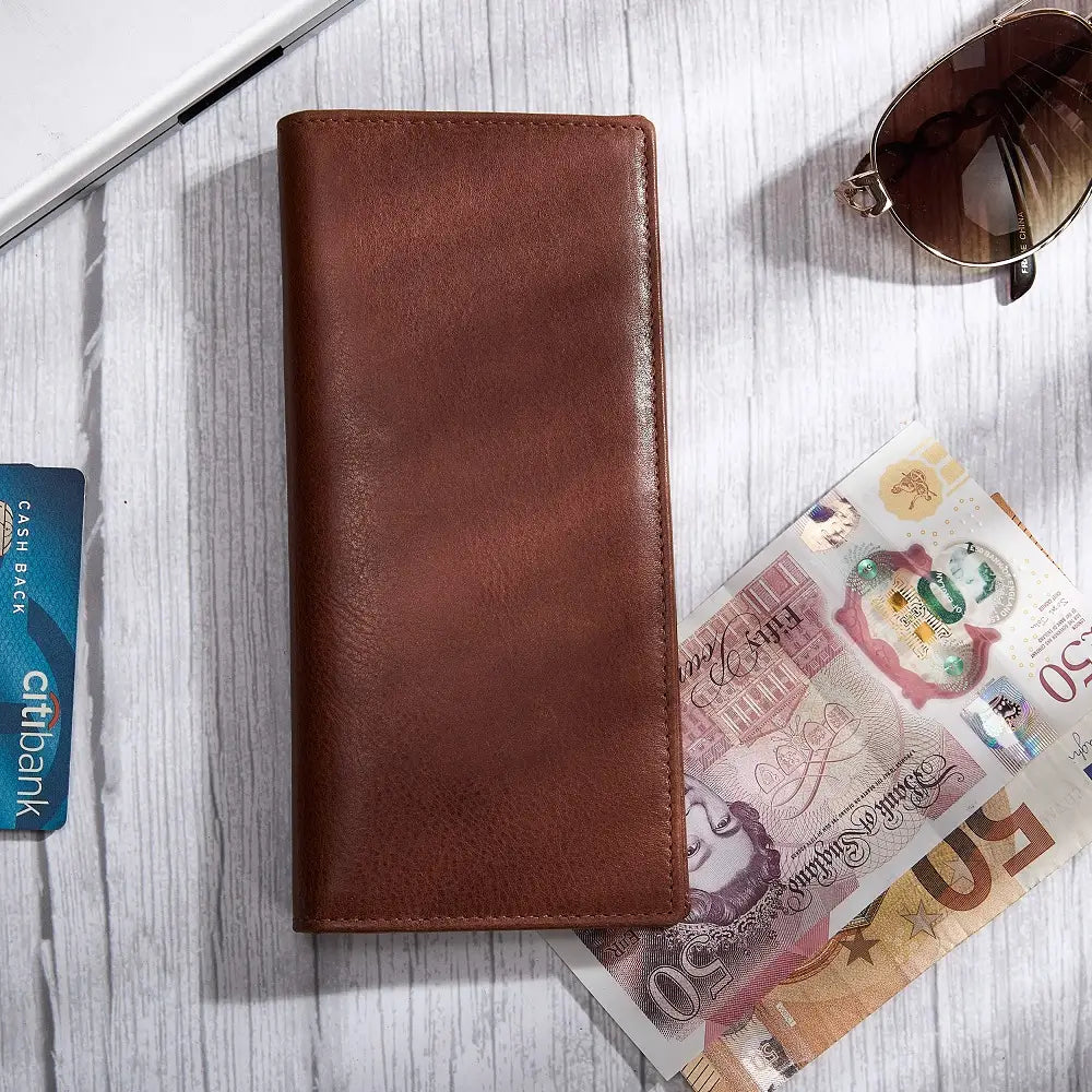 Chestnut leather wallet with banknotes and a Citi card on a wooden surface