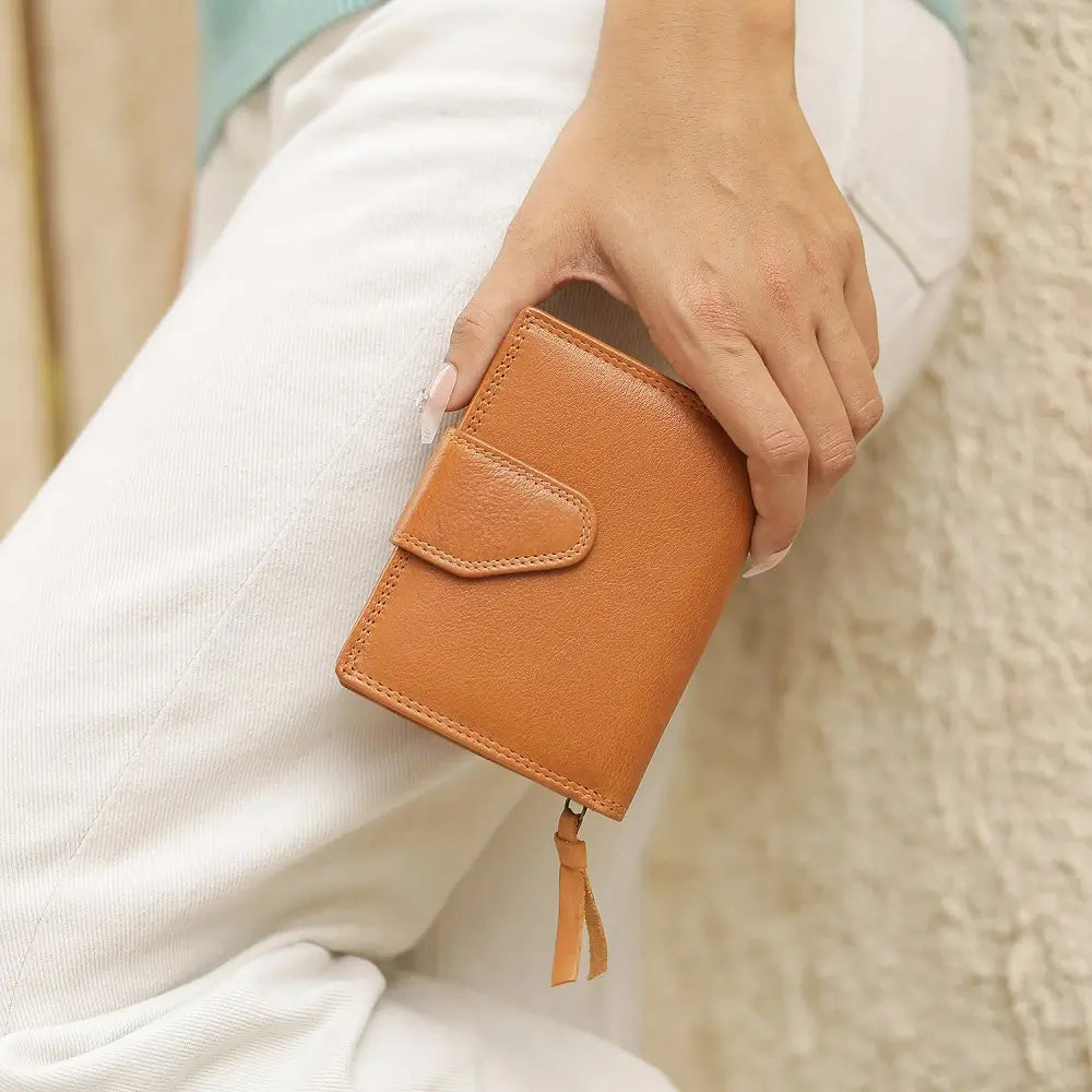 cognac leather wallet held by a person wearing a white sweater.