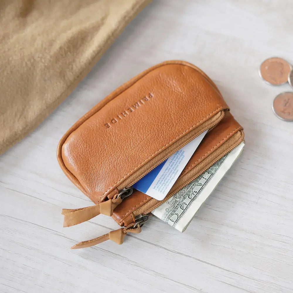 Cognac leather wallet with money and coins on a light wooden surface