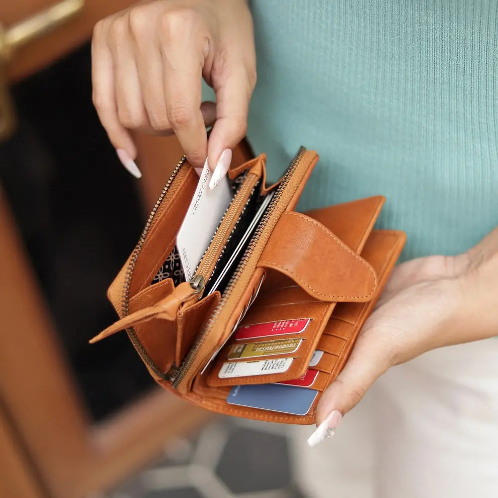 Cognac wallet with cards held open by a hand against a blurred background