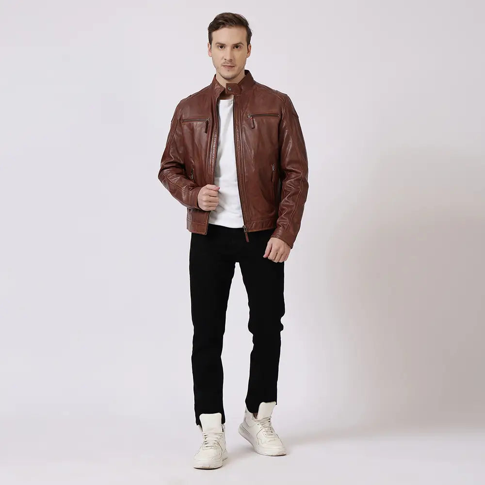 Man wearing a cognac leather jacket, white shirt, black pants, and white sneakers on a light gray background