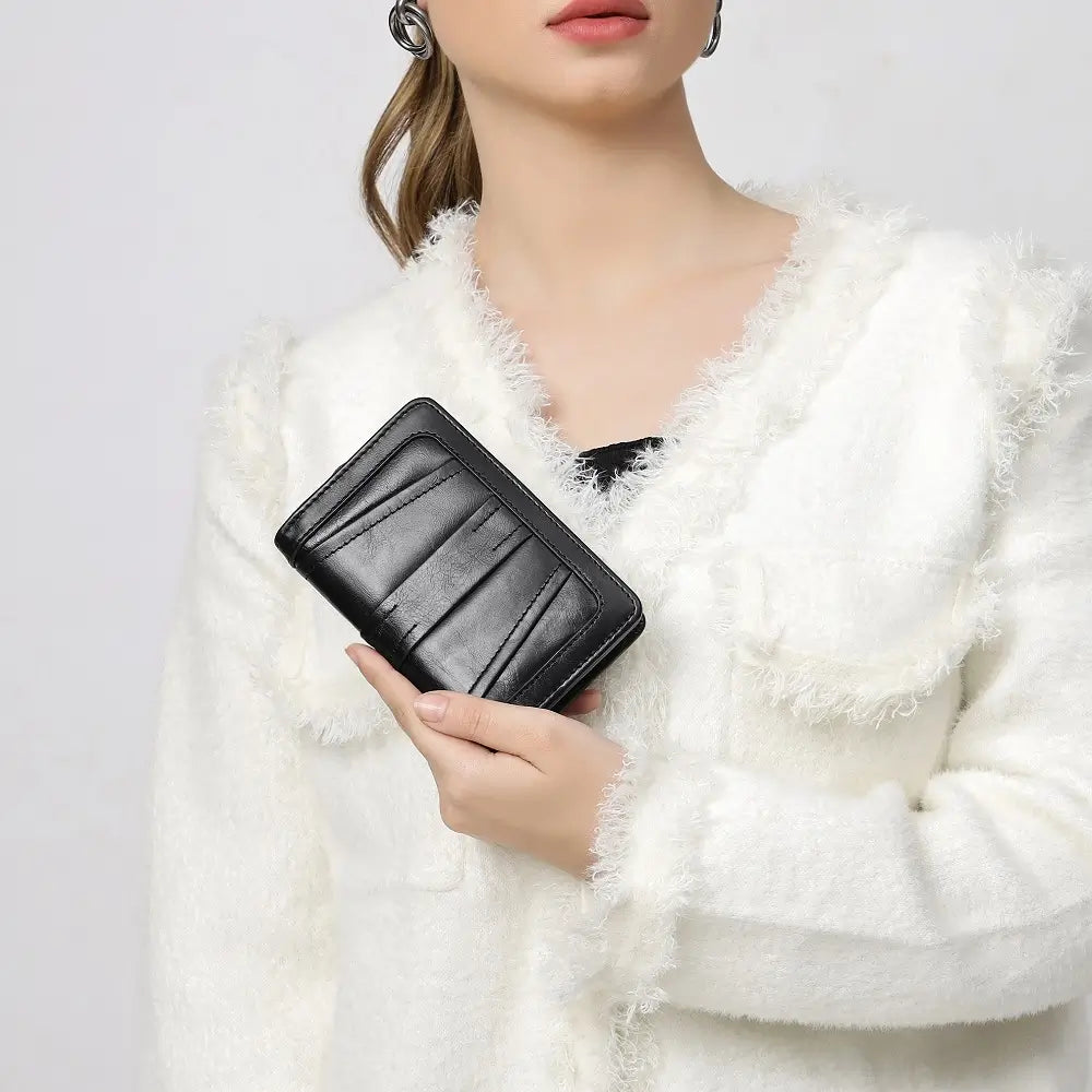 Person holding a black wallet against a white background
