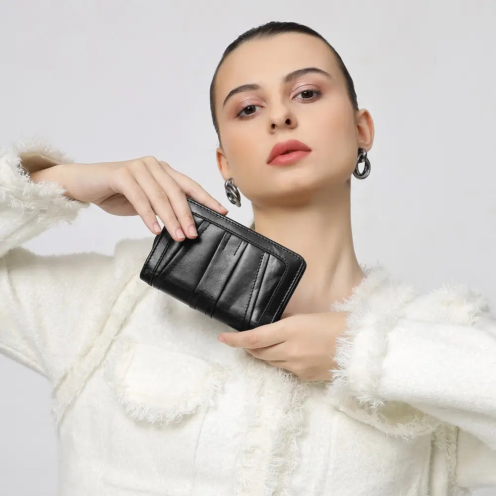 Woman holding a black purse against a plain background