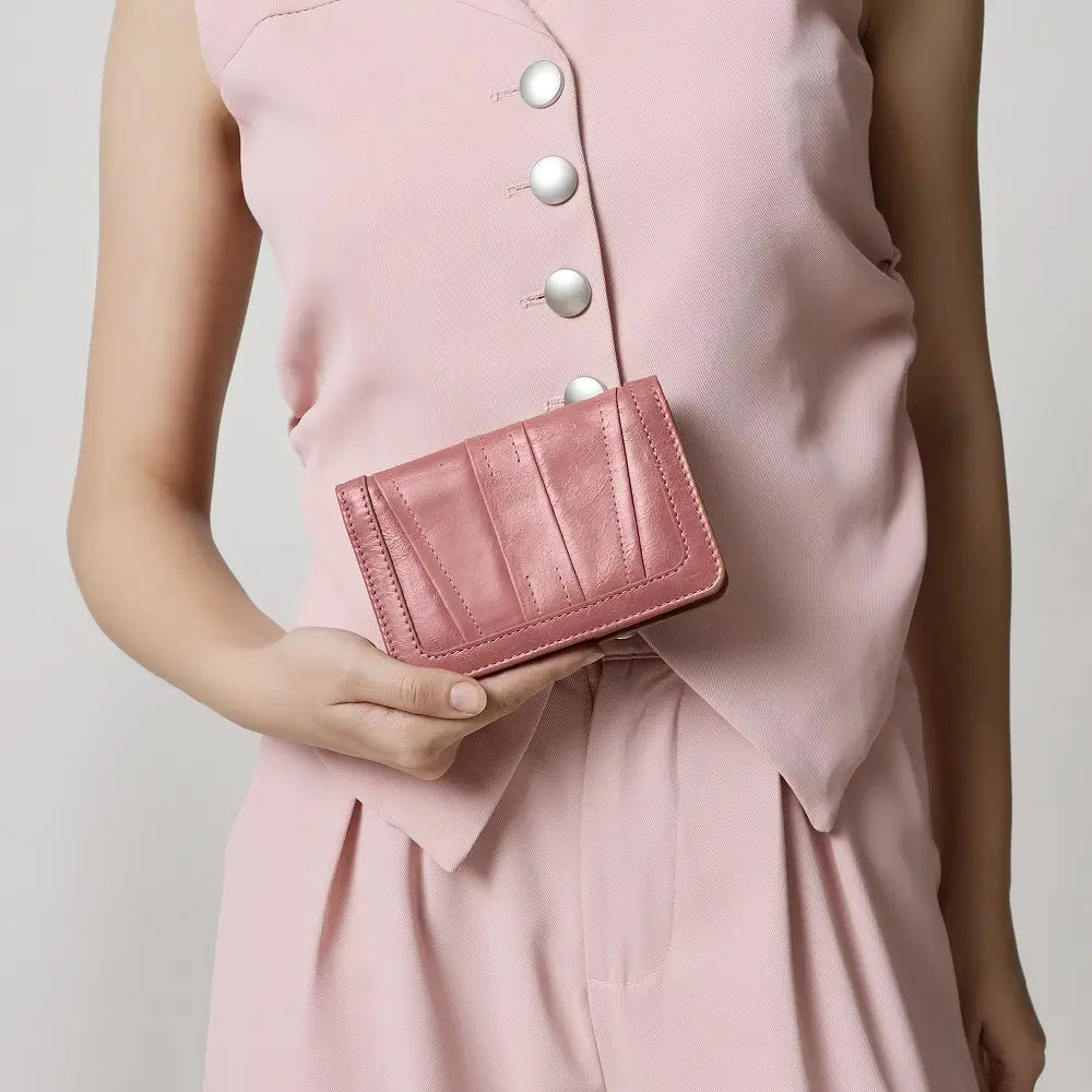 Person wearing a pink dress holding a matching brown purse  against a neutral background