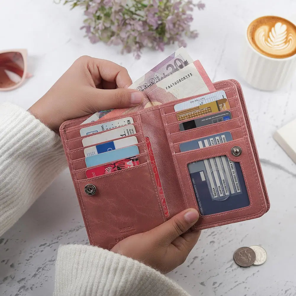 Person holding a brown purse  with cards and money on a light surface with flowers and a cup in the background