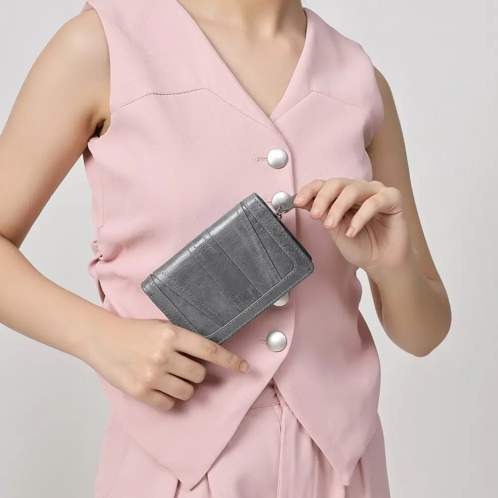 Person holding a Grey Purse against a plain background