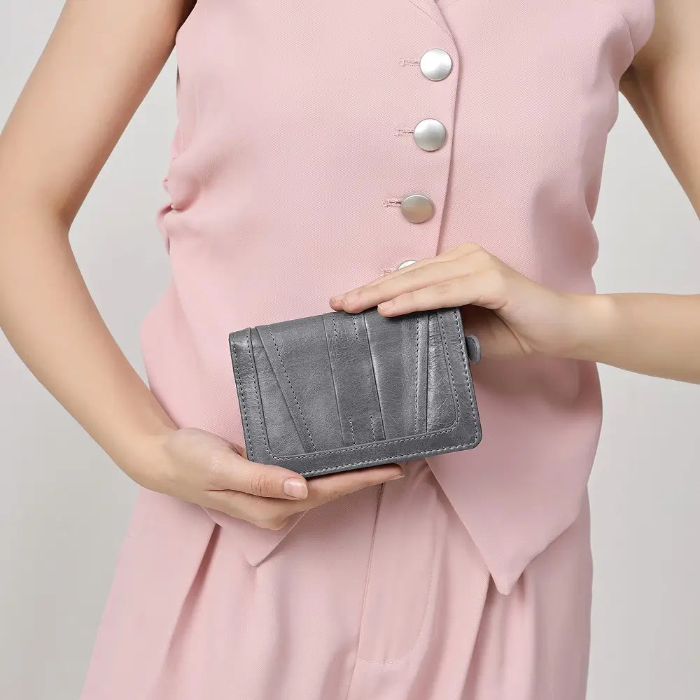 Person holding a Grey Purse against a plain background