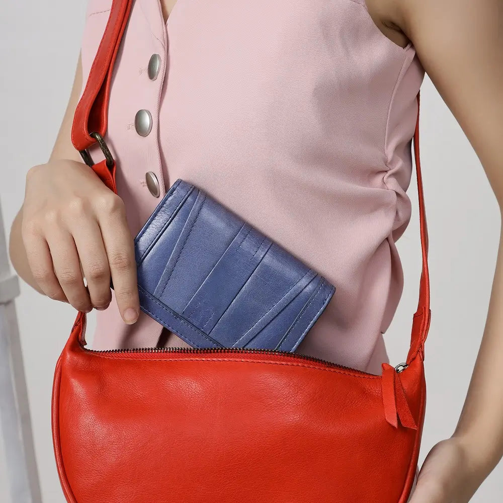 Person holding a red handbag with a Grey Purse inside, wearing a pink sleeveless top.