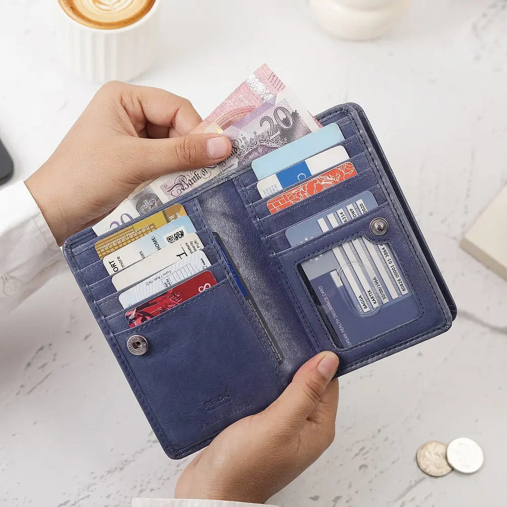 Open Light Grey Purse with cards and money held by a hand on a light surface.