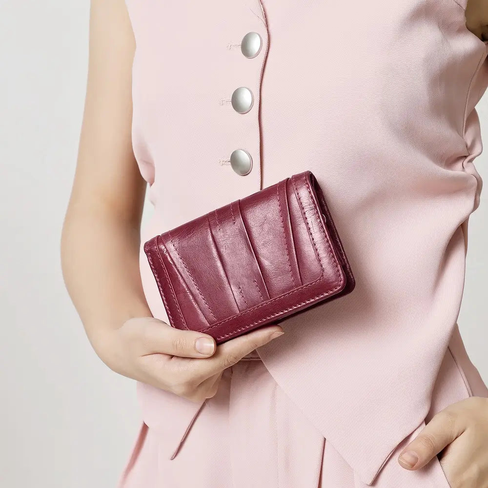 Person holding a maroon purse against a light pink background
