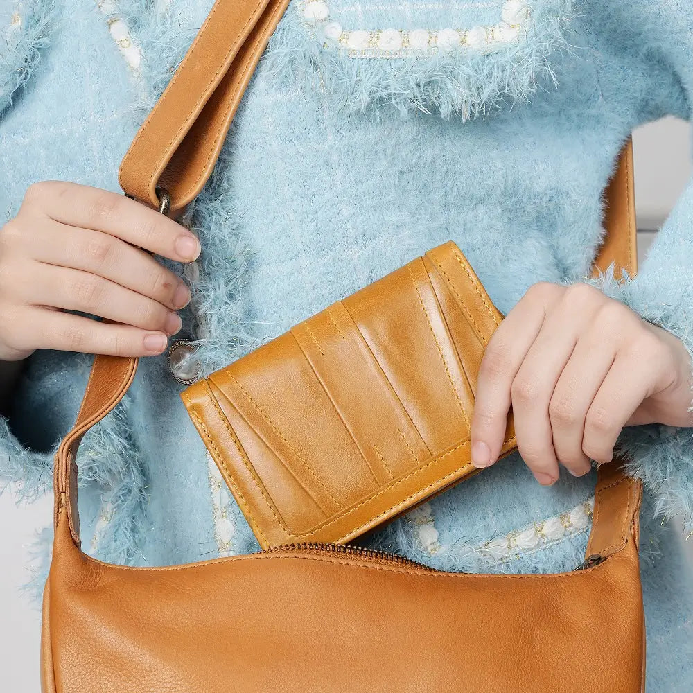Mustard Purse held by a person with a blue textured background