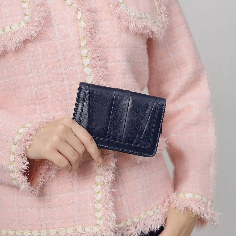 Person holding a Black Purse against a pink textured background