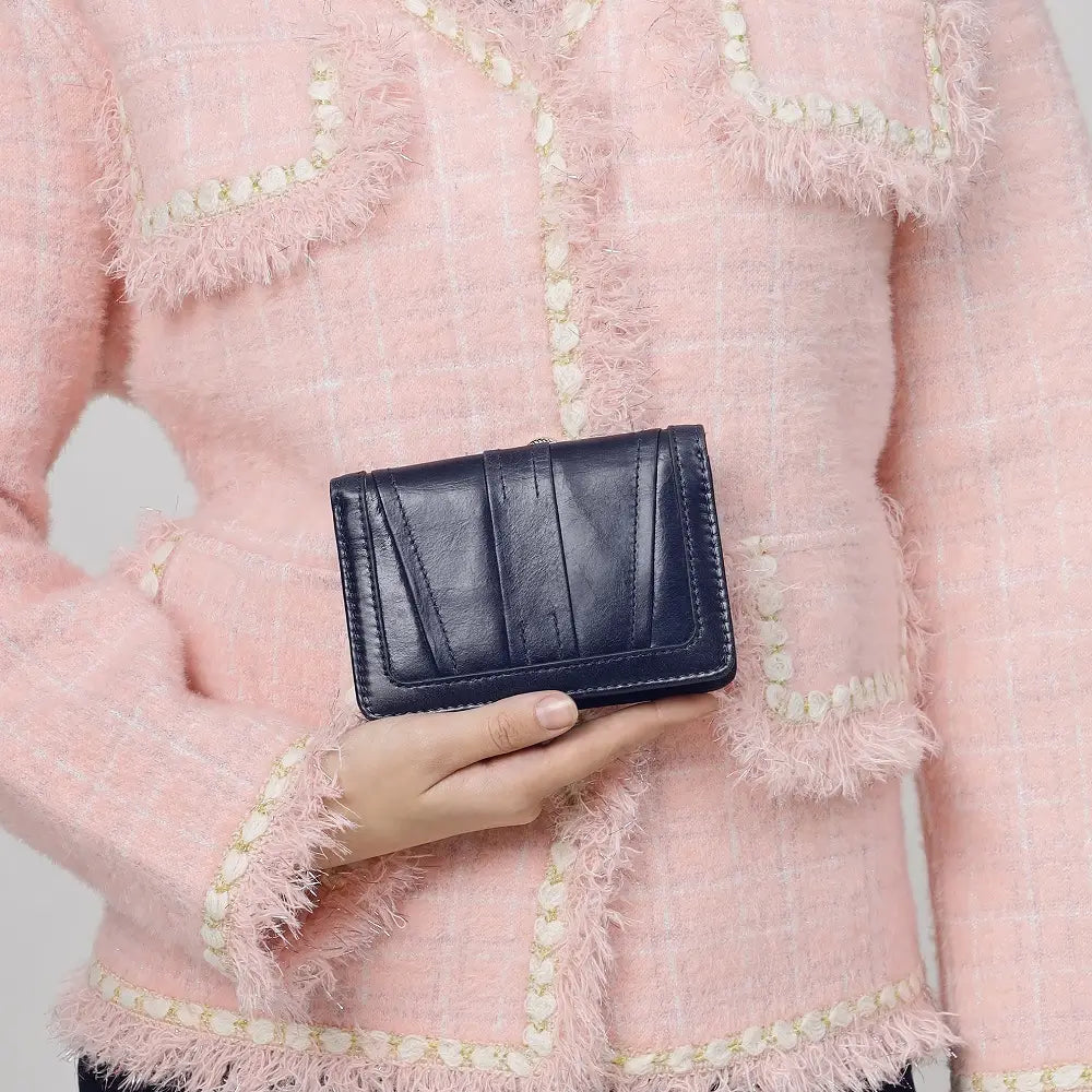 Person holding a black wallet against a pink textured background