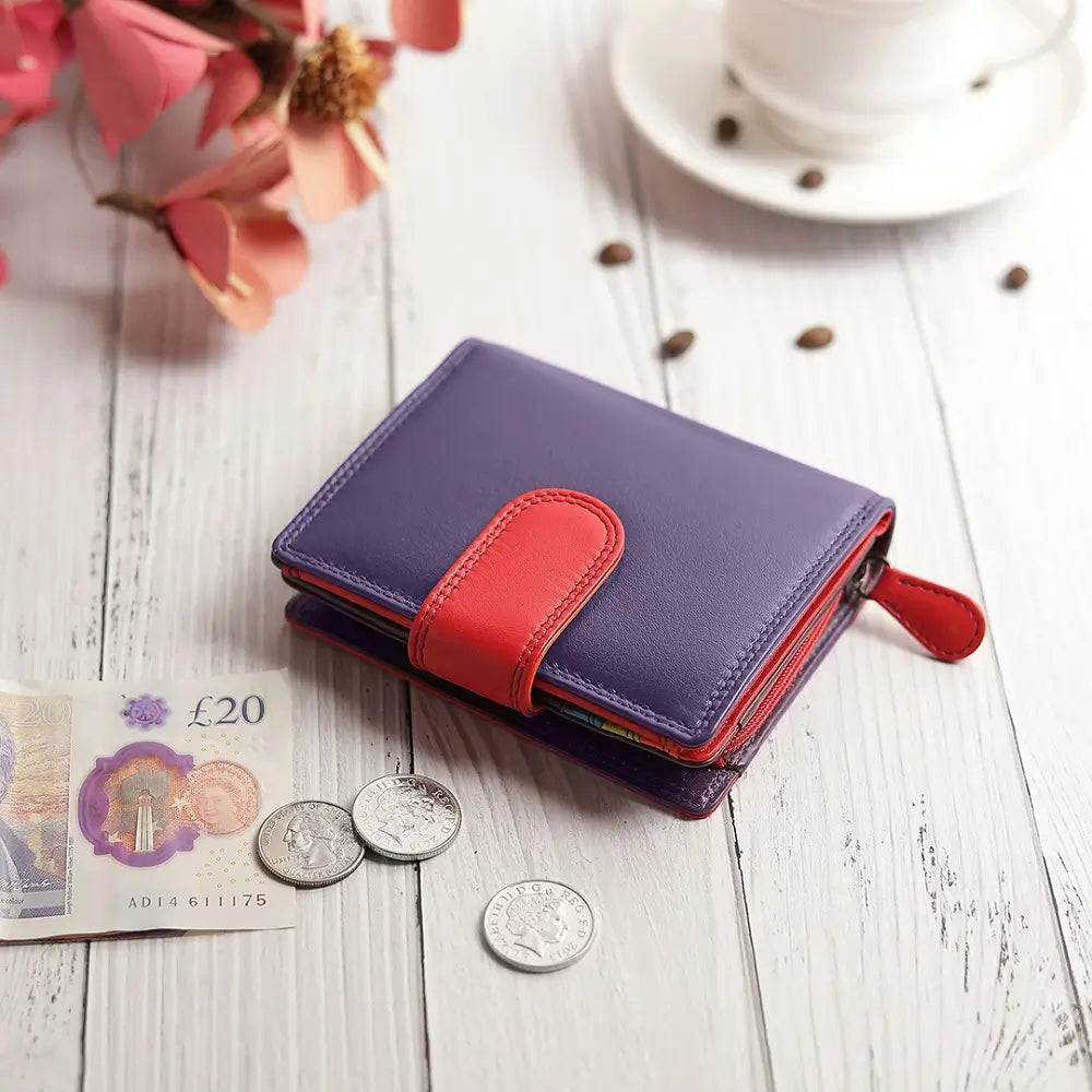 Grape wallet on a wooden surface with coins and a banknote.