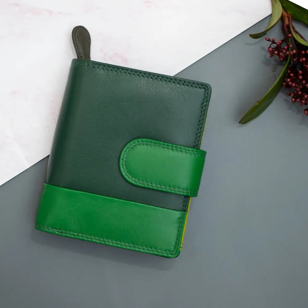 Green leather purse on a gray surface with a white background