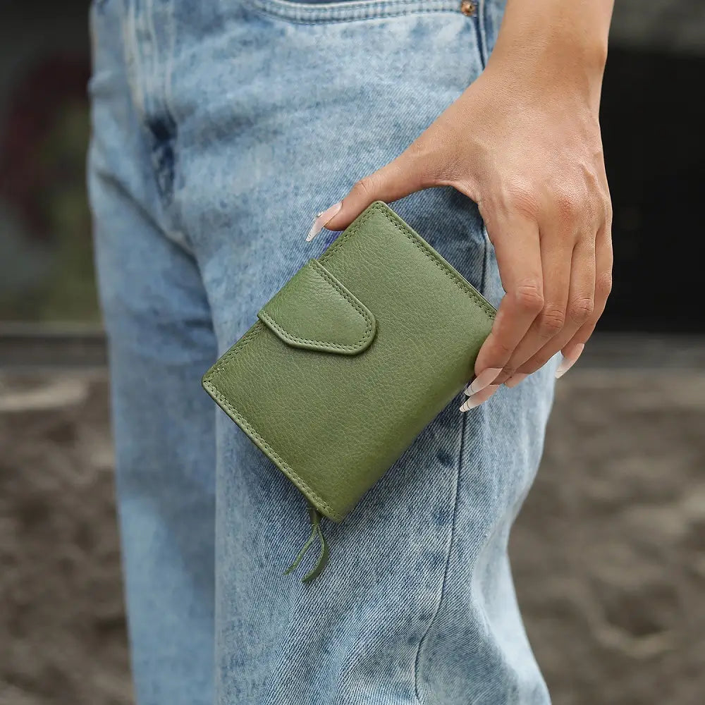 Green wallet held by a person wearing blue jeans