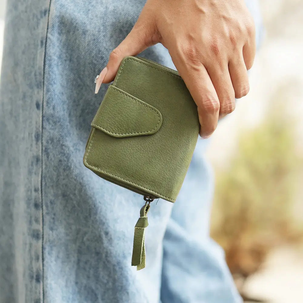 Green wallet held by a person wearing a light blue denim jacket.